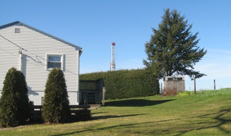 The drilling rig pokes up behind the hedges of a home near Evans City, PA.